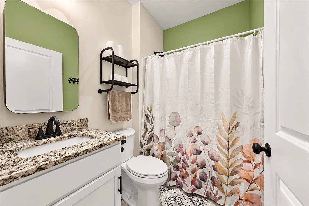 Guest bathroom with a white vanity, granite countertop, and sage green accent wall