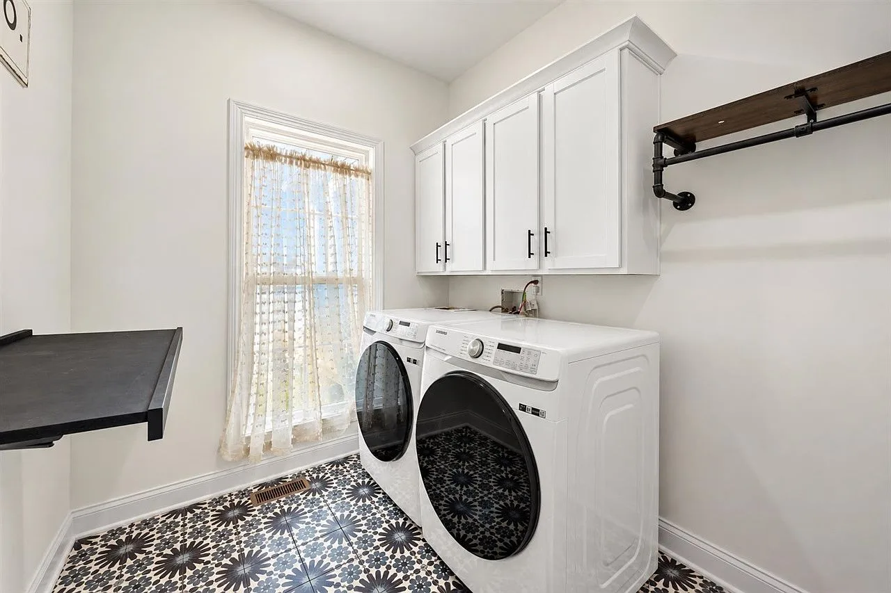 Laundry room with white shaker cabinets, matte black hardware, and an industrial pipe hanging rack