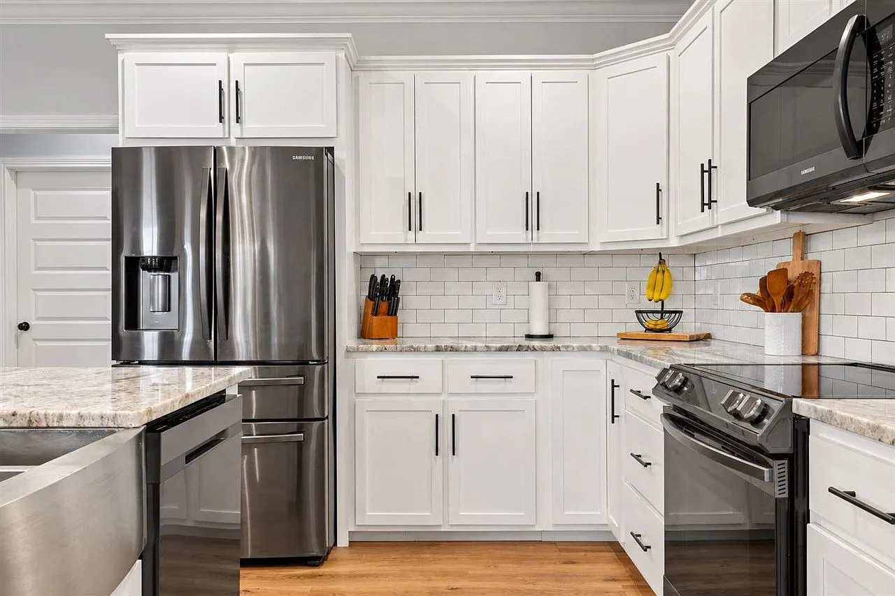 Kitchen with white Shaker cabinets, subway tile backsplash, and light granite countertops