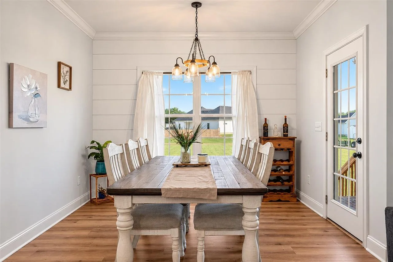 Dining room with a shiplap accent wall, natural light, and a glass door