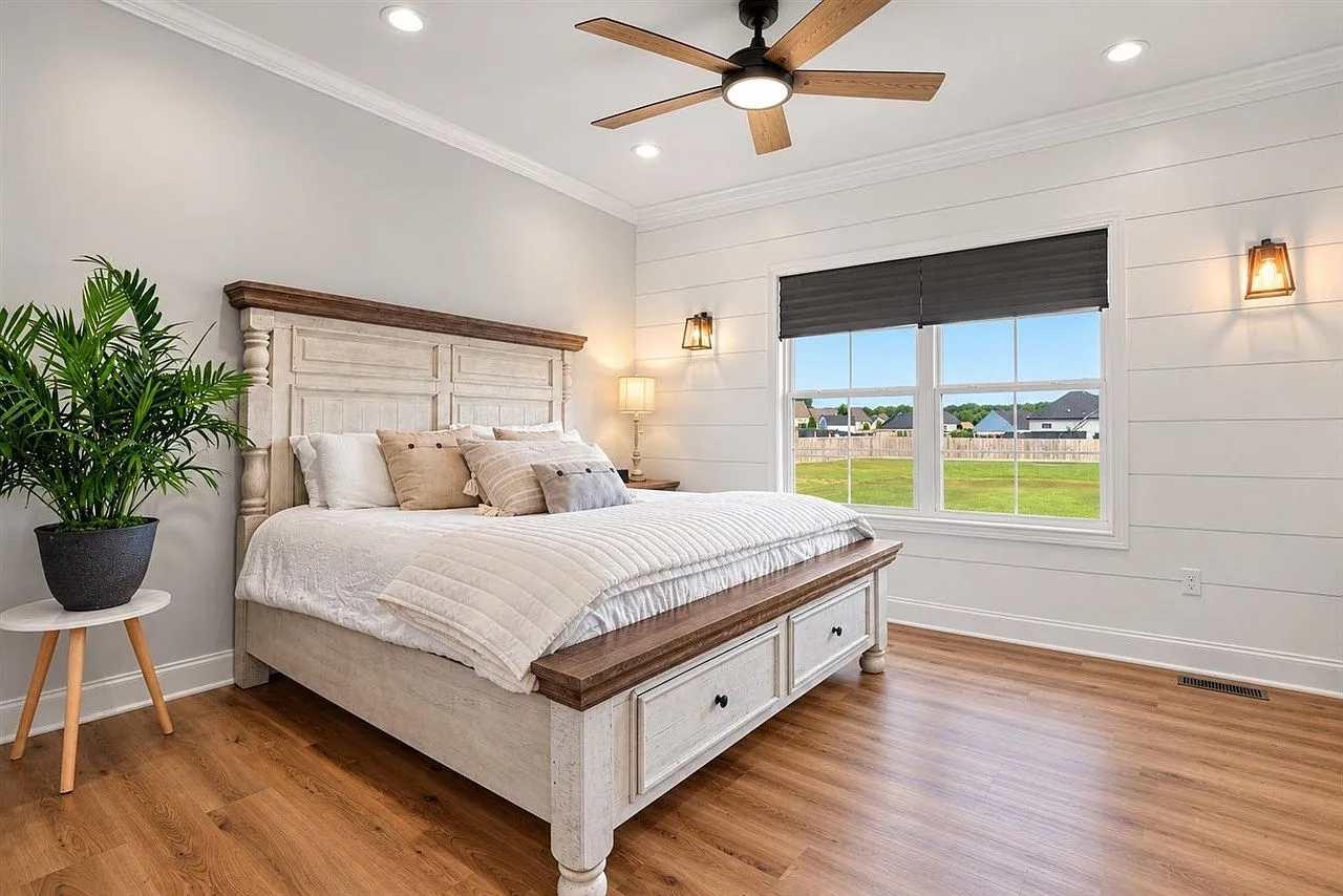 Primary bedroom with a white shiplap accent wall and plentiful natural light