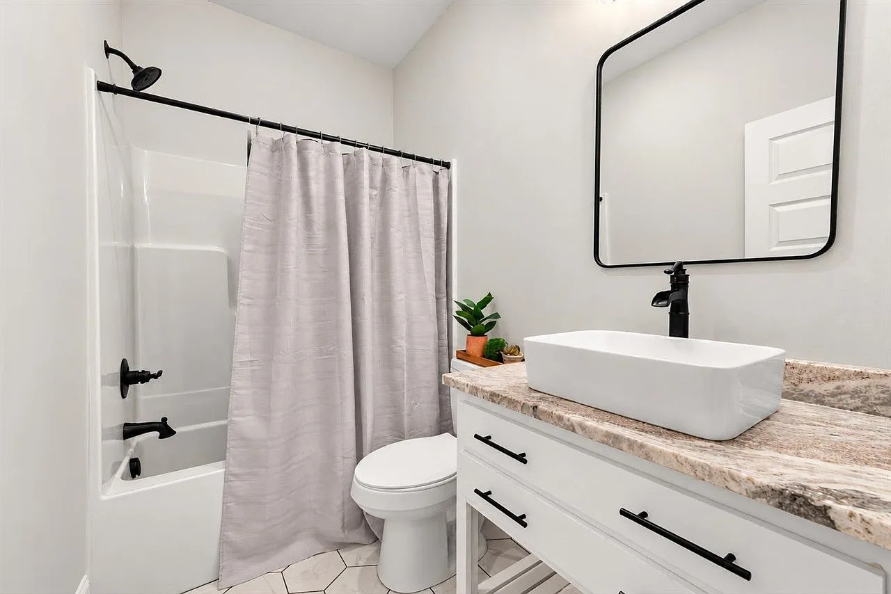 Bathroom with a white vanity, vessel sink, matte black hardware, and hex floor tile