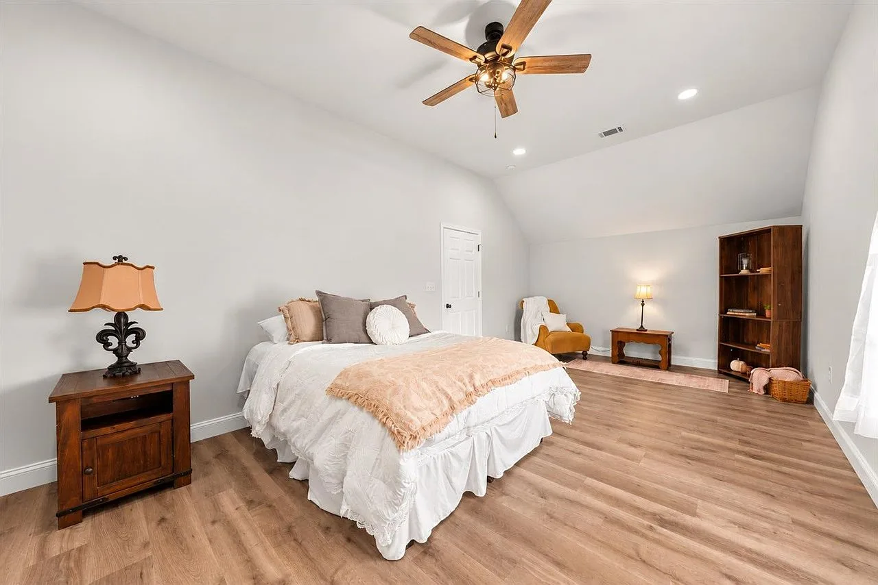 Bedroom with a vaulted ceiling, natural light, and a tucked-away reading chair