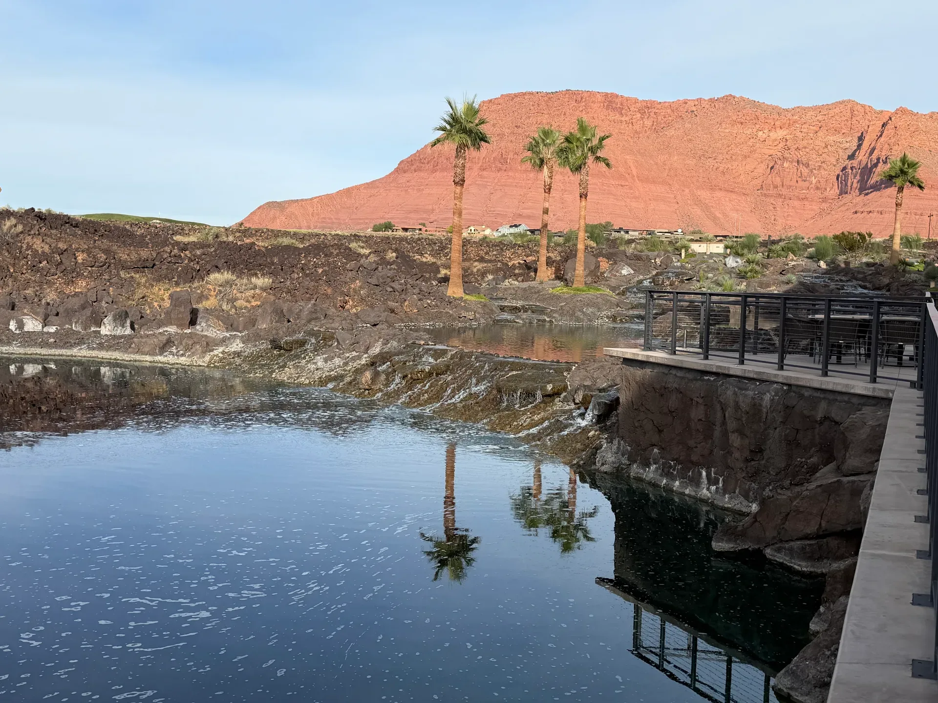 Desert pond patio at Black Desert with palms and red rock mountains behind