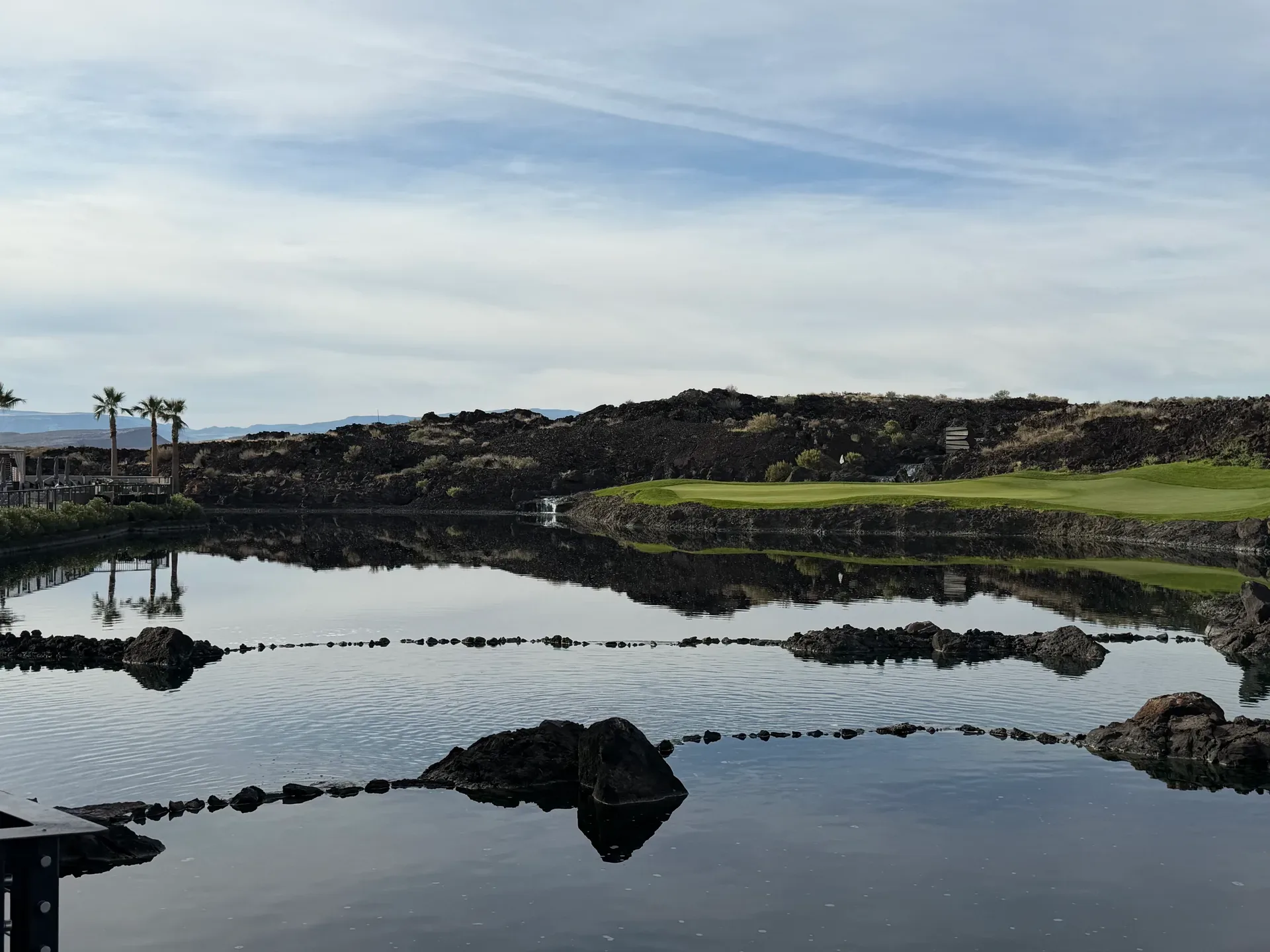 The Black Desert championship golf course with a reflection pond between dark volcanic rock formations