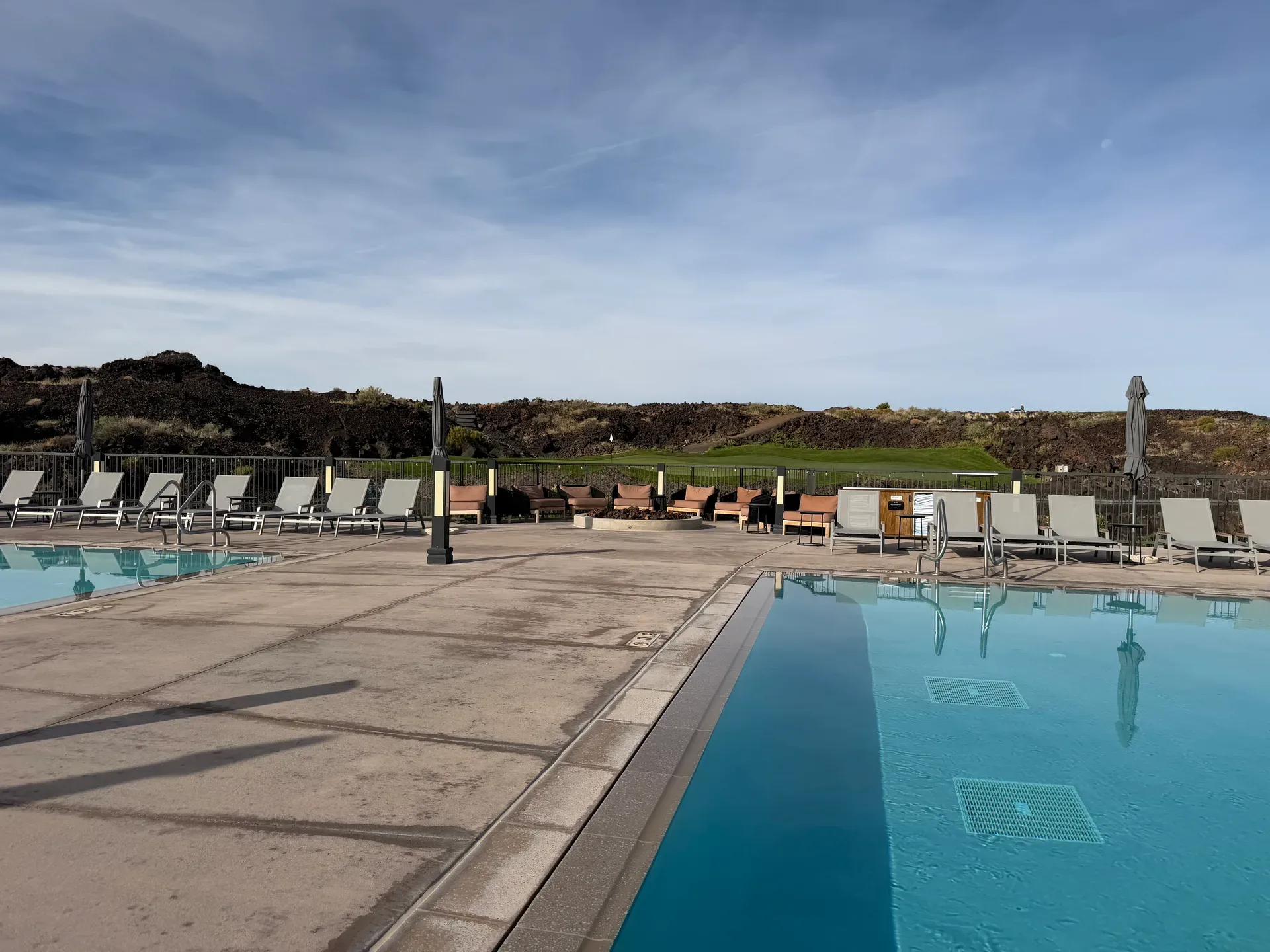 Resort pool deck at Black Desert with lounge chairs and a fire pit seating area