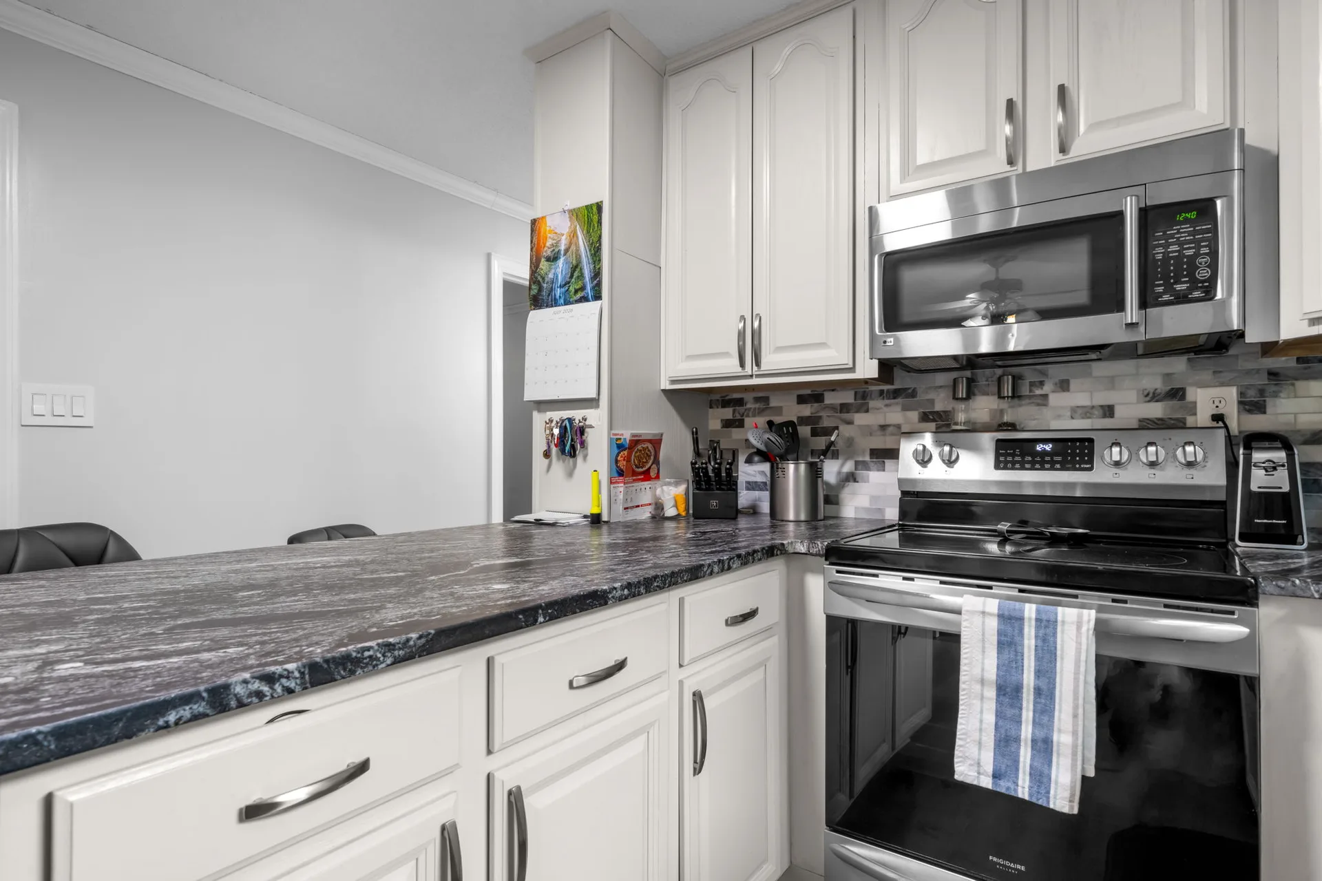 Kitchen counter and stainless steel appliance run with a dark leathered granite countertop
