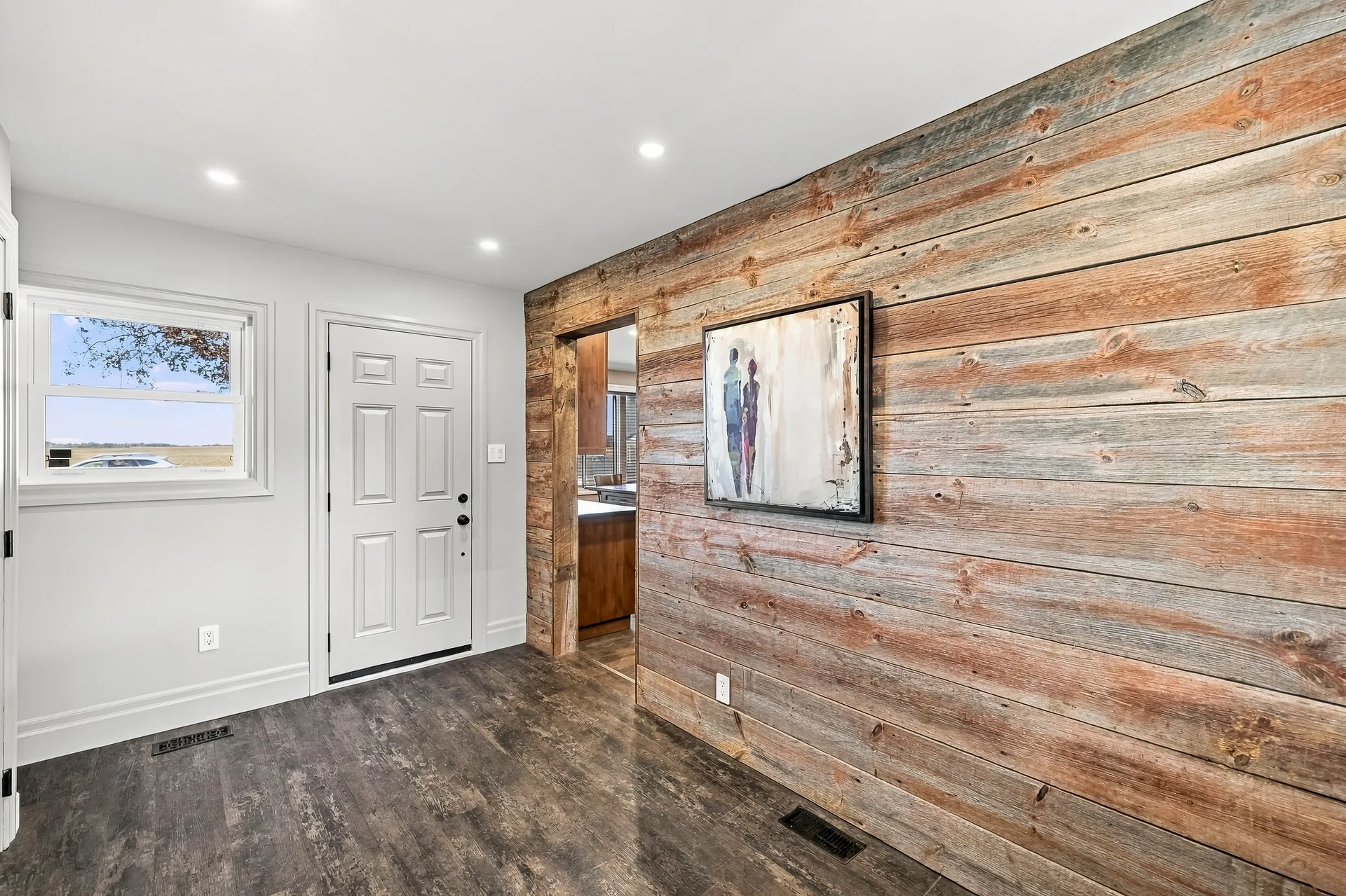 Entryway with reclaimed wood accent wall and dark plank flooring