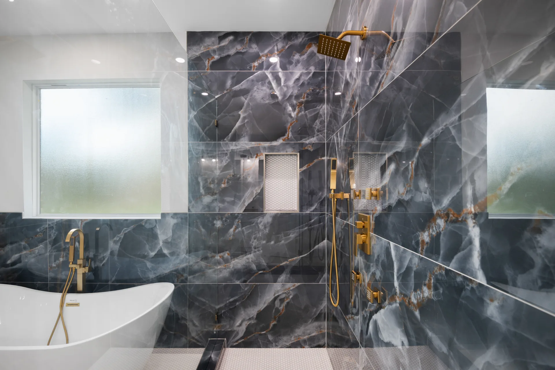 Primary bathroom with freestanding tub, glass spa shower and gold fixtures