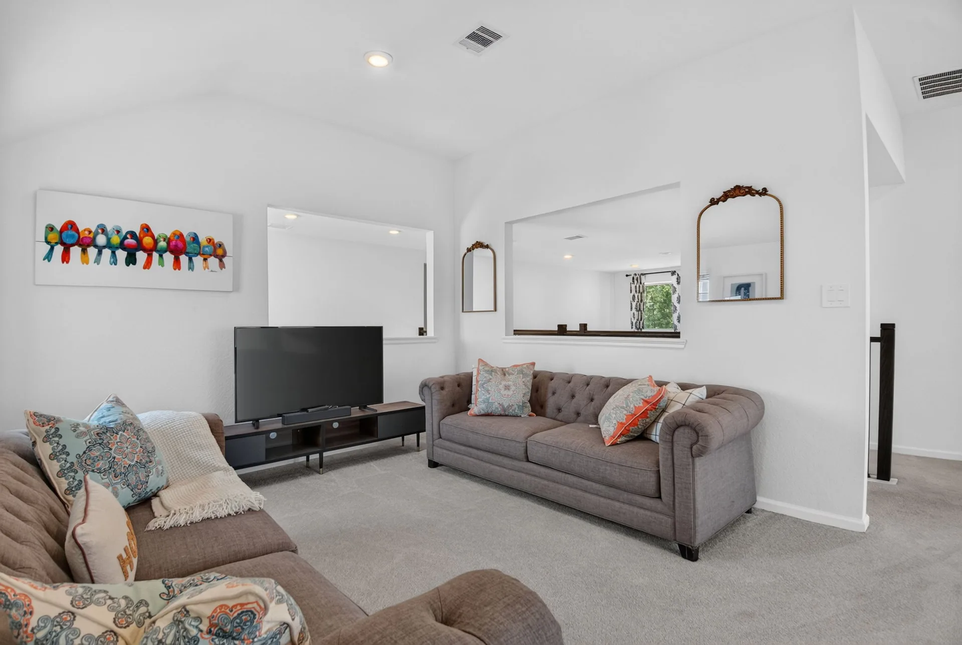 Bonus living room with architectural wall cutouts overlooking the space beyond
