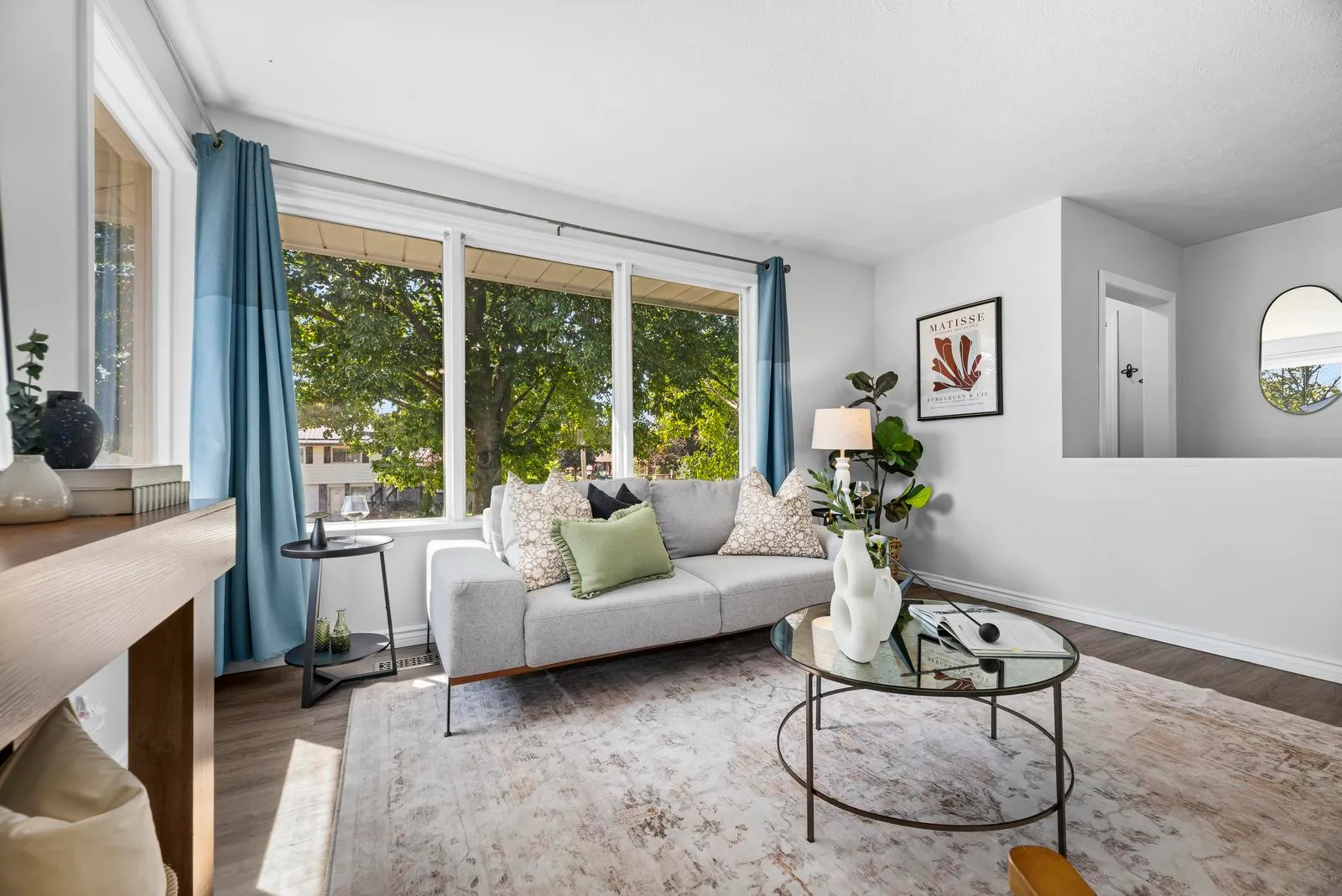 Living room with light grey walls, hardwood flooring, and natural daylight from picture windows