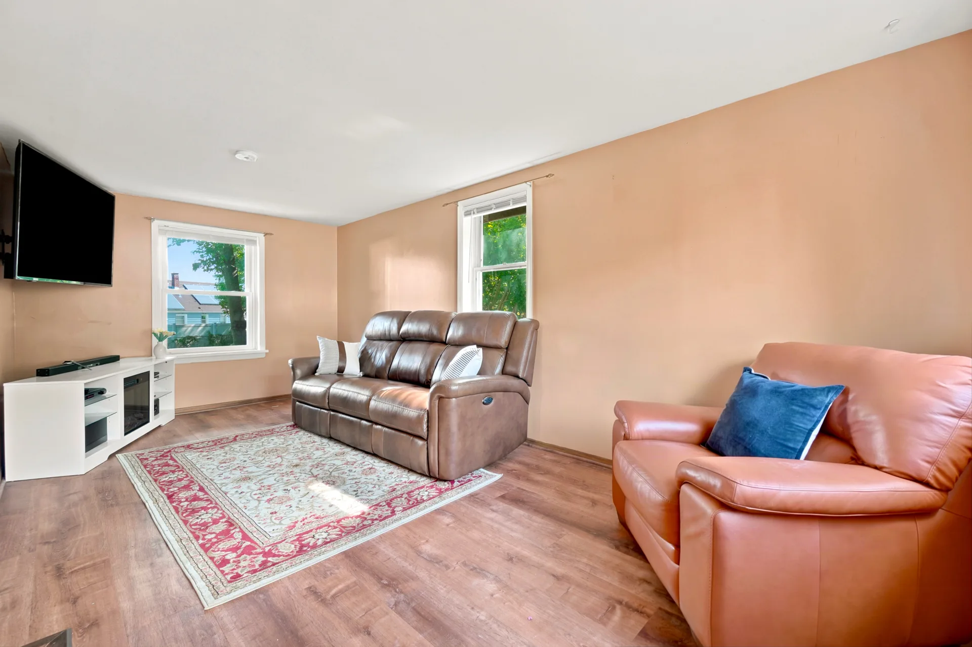 Family room with light walls, wood-look flooring, and natural daylight from windows