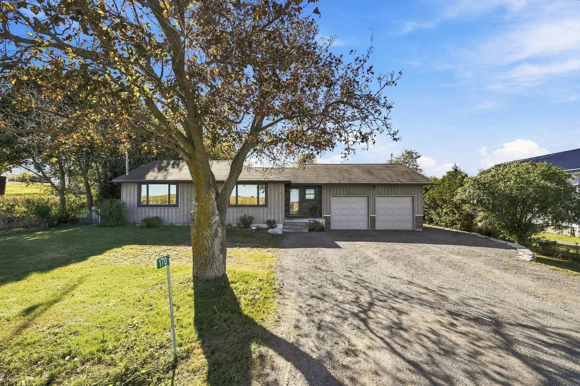 Wide front view of the bungalow with stone accents, double garage and gravel drive