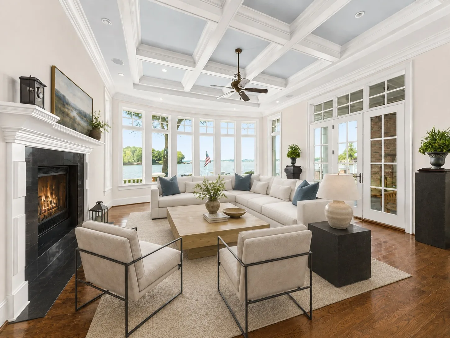 Grand living room with coffered ceiling, hardwood floors, fireplace, and panoramic lake views