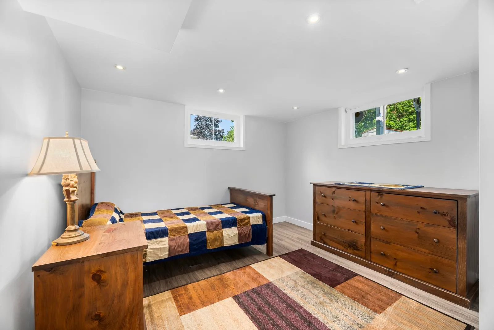 Basement guest bedroom with neutral walls and recessed ceiling lighting
