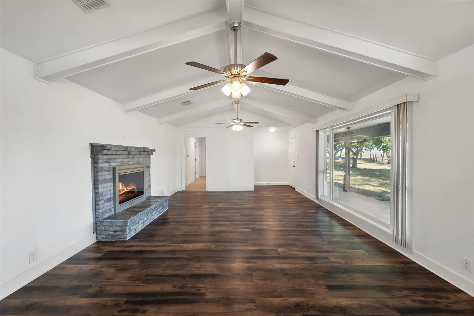 Living room with vaulted ceiling, exposed beams and stone-faced fireplace