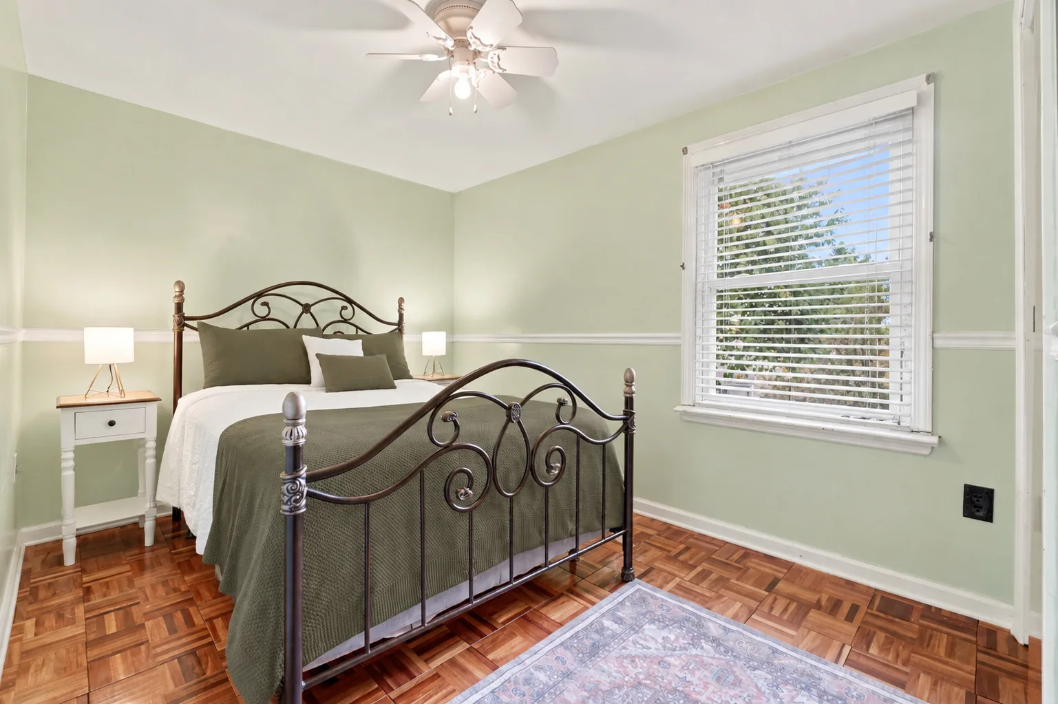 Upstairs bedroom with parquet hardwood floors and pale green walls