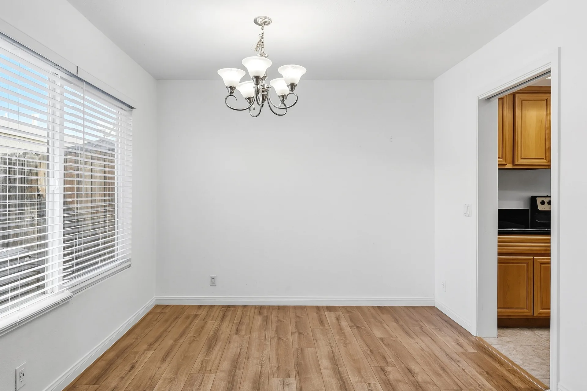Dining space at 8 Silverwood beneath a multi-bulb chandelier with daylight from a side window
