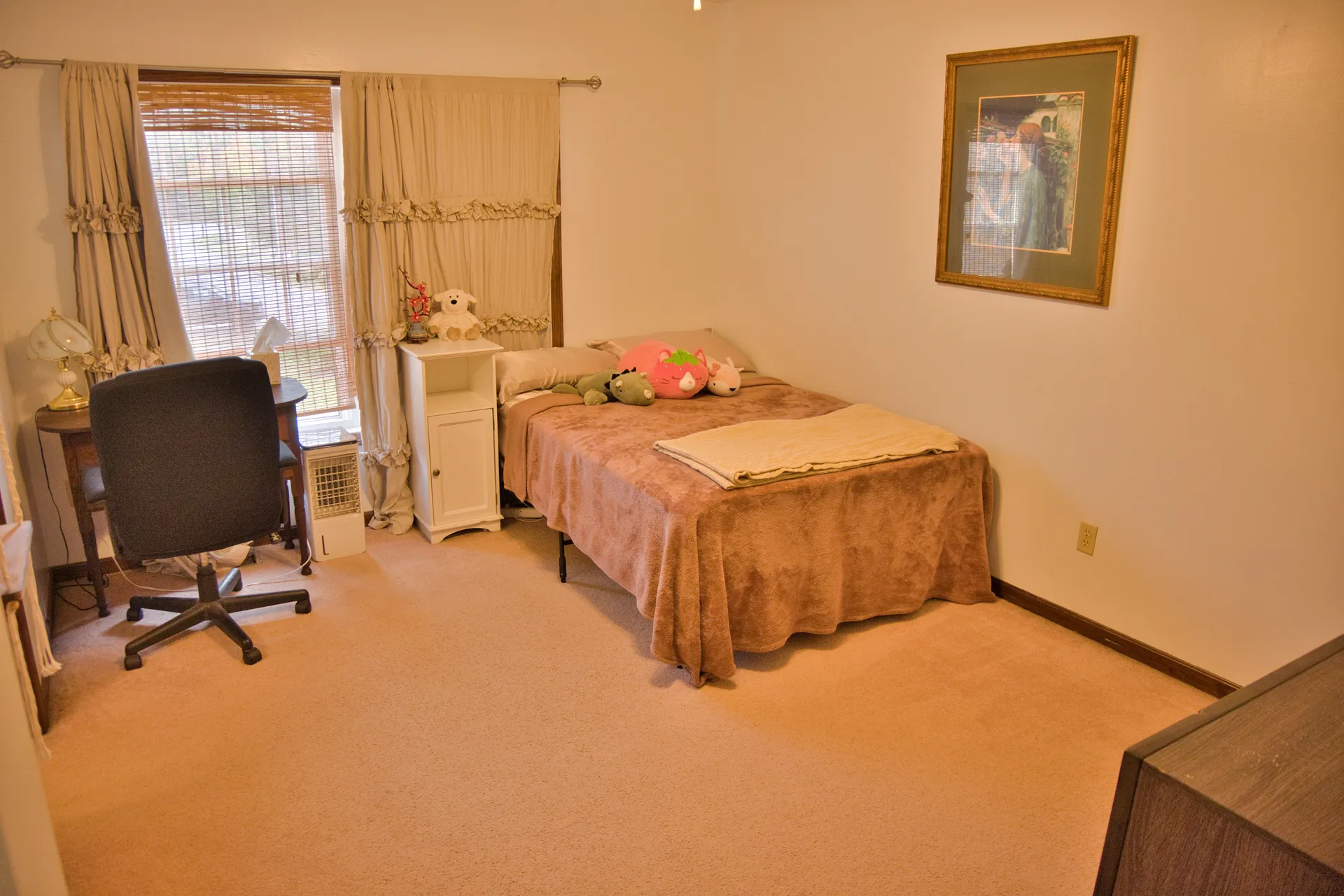 Secondary bedroom with a bed, desk, and natural light from the window