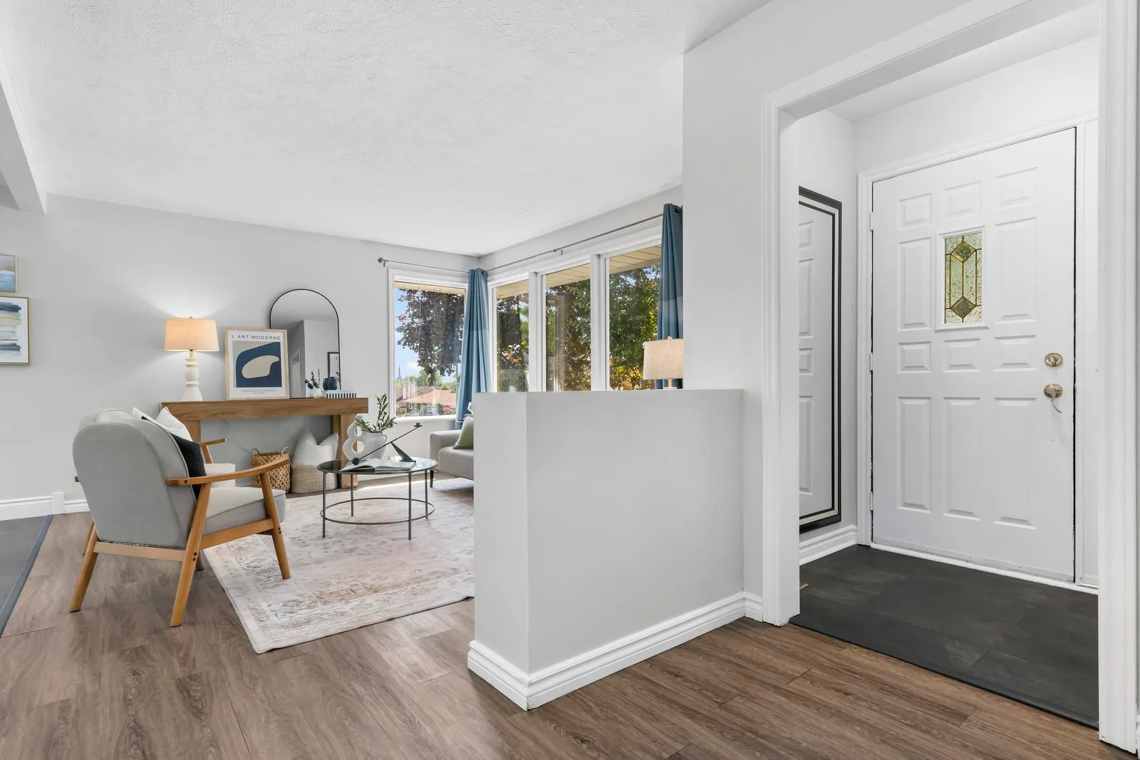 Entry and living room with open floor plan, neutral walls, and wood-look laminate flooring