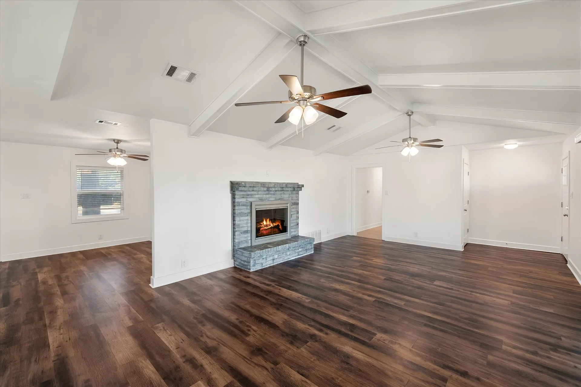 Vaulted living room with exposed beams and a grey stone-faced fireplace