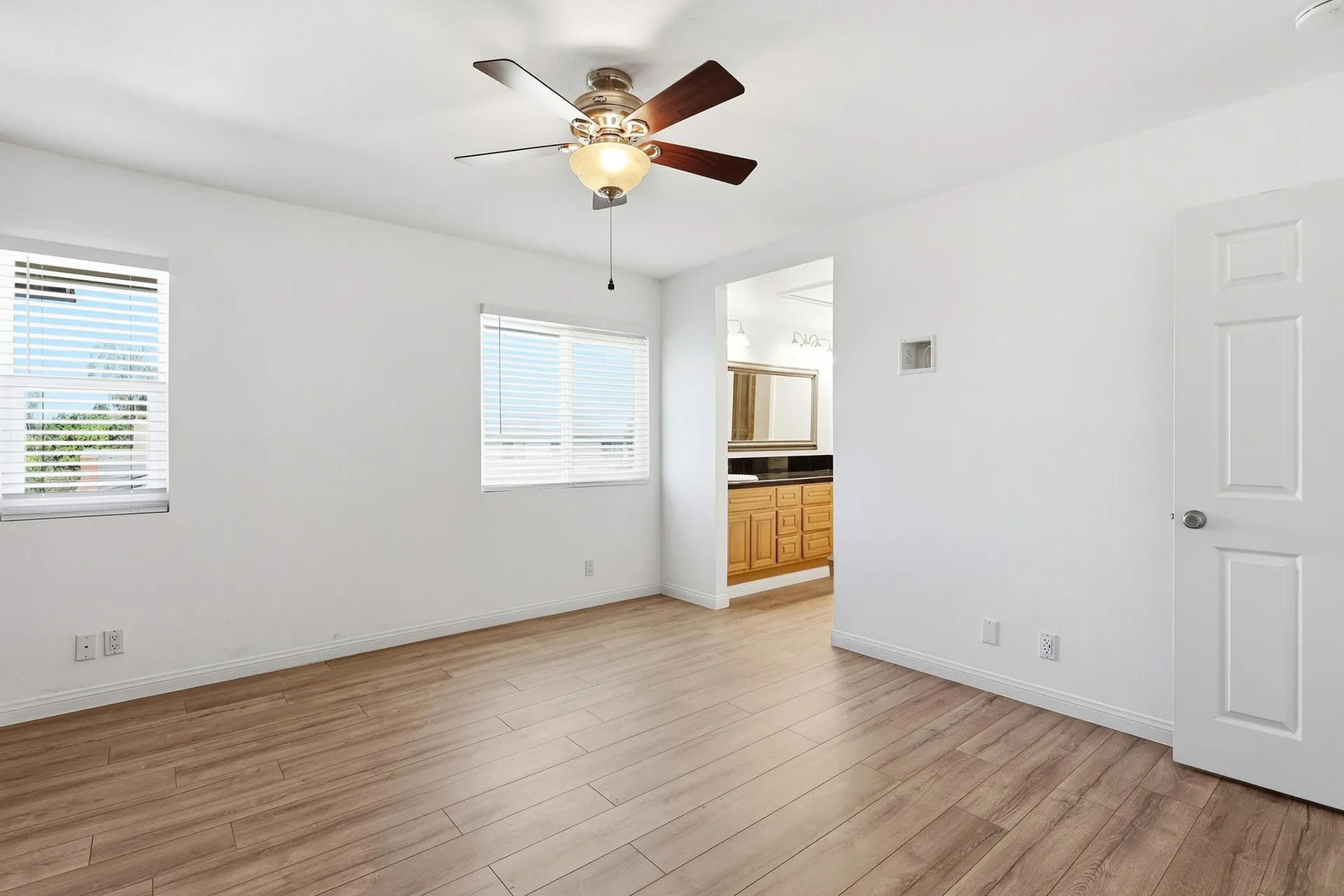 Primary bedroom at 8 Silverwood looking toward the ensuite bath with two windows and wood flooring