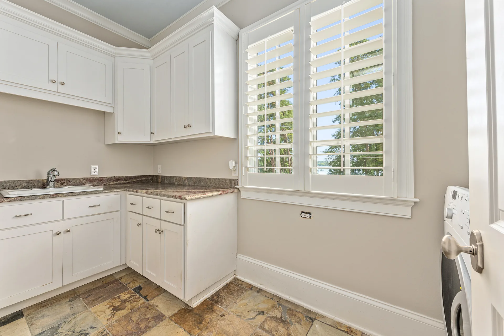 Laundry room with white cabinetry and granite countertops