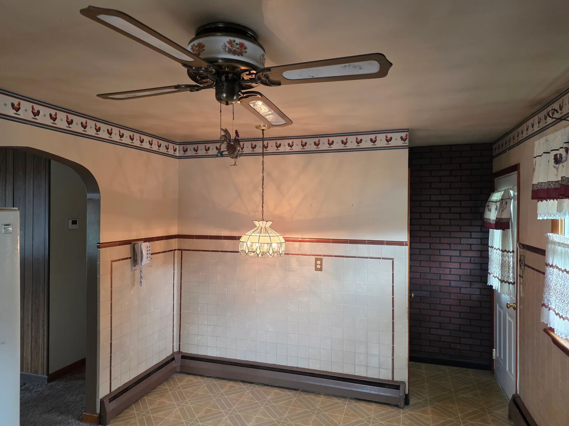 Dining area with tiled wainscoting and brick accent wall