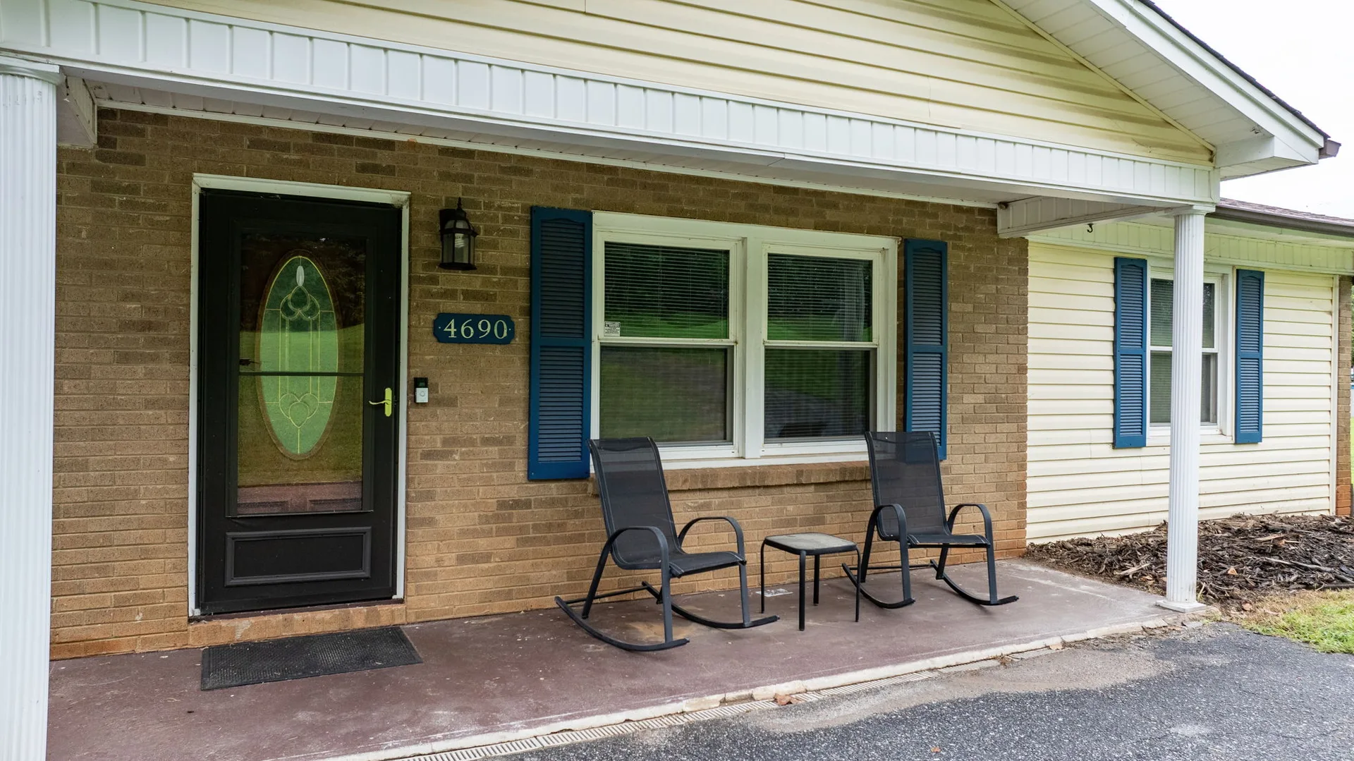 Front porch entrance of the home at 4690 Worth Pl with brick facade, white siding, and blue shutters