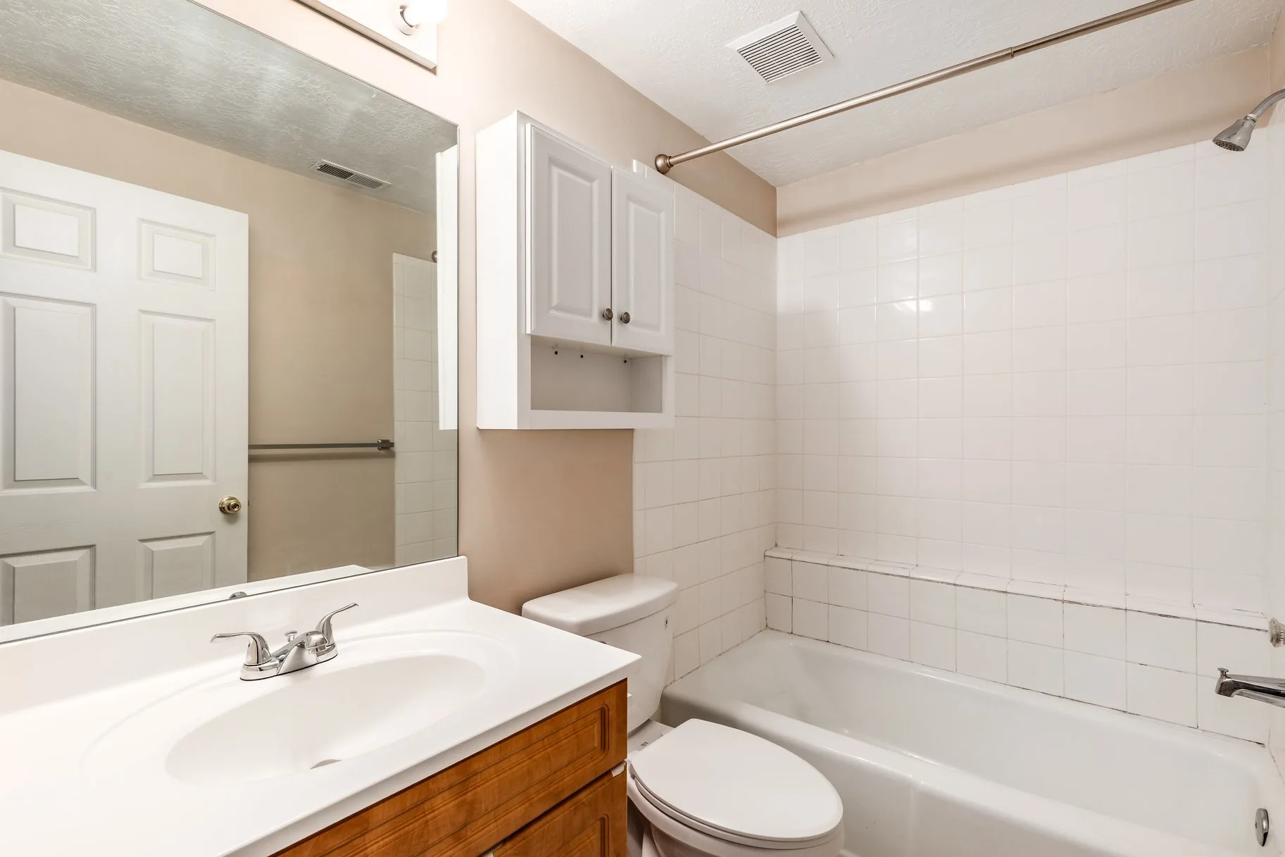 Bathroom with wooden vanity cabinet and tile surround