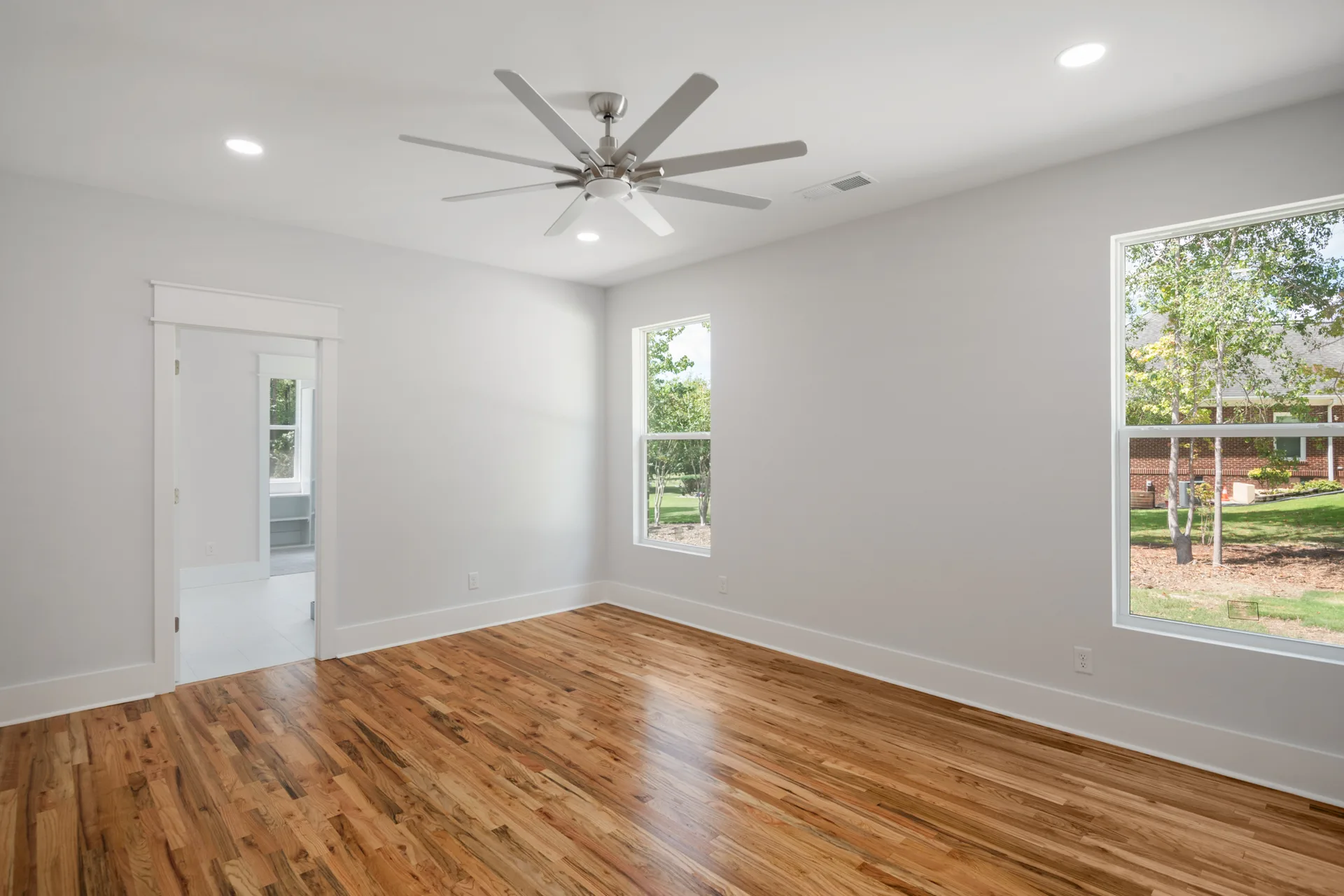 Primary bedroom with two windows and ceiling fan