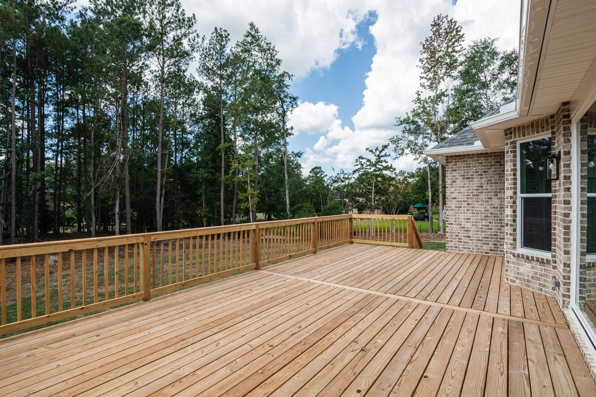 Elevated wooden deck behind the home overlooking the back yard