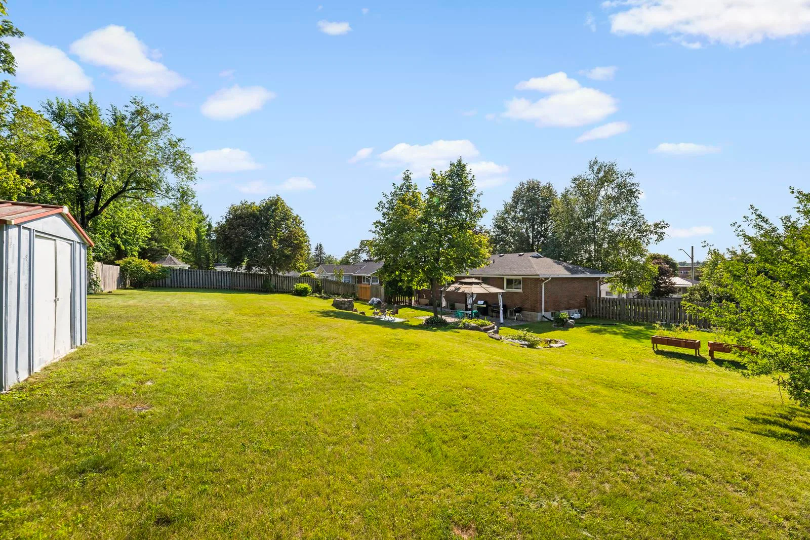 Expansive backyard lot with gazebo, pond, and mature trees showing two combined lots