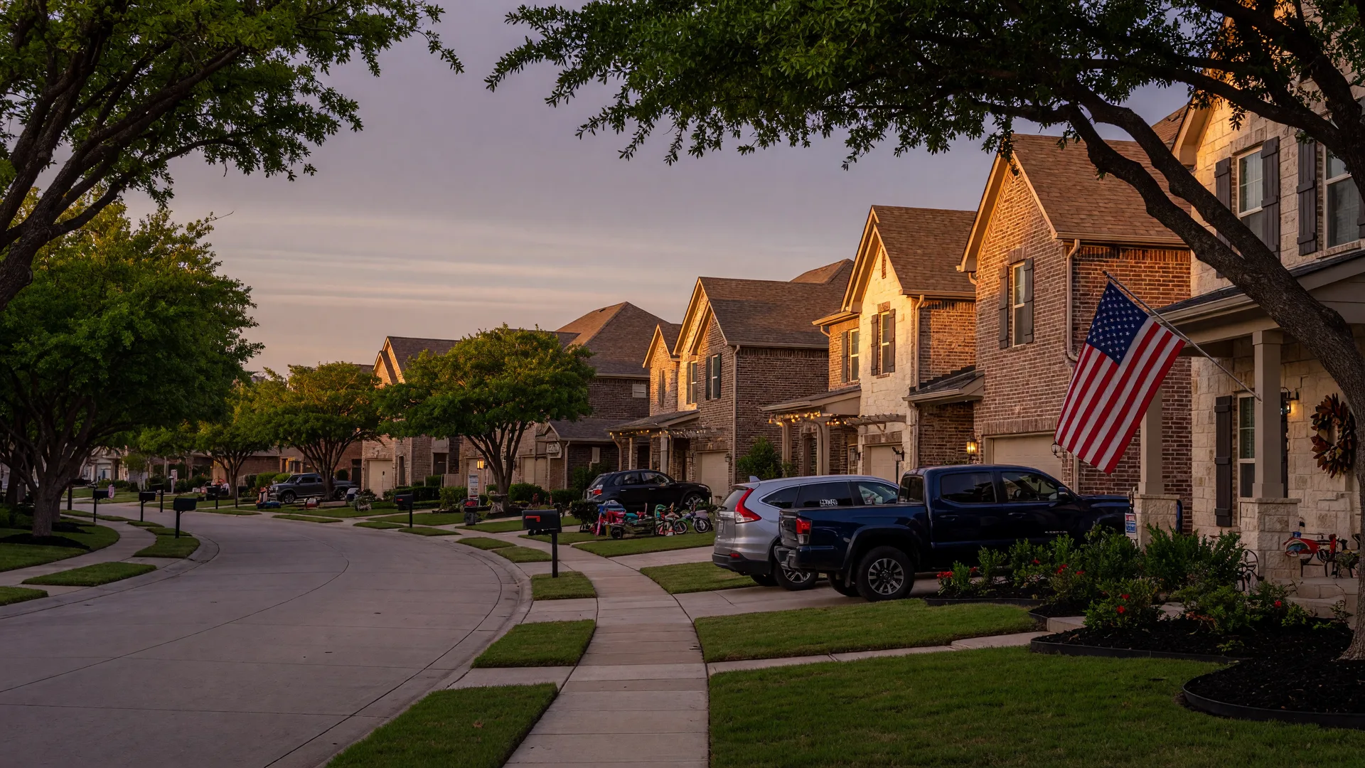 A North Texas residential community street at golden hour with an American flag on a front porch