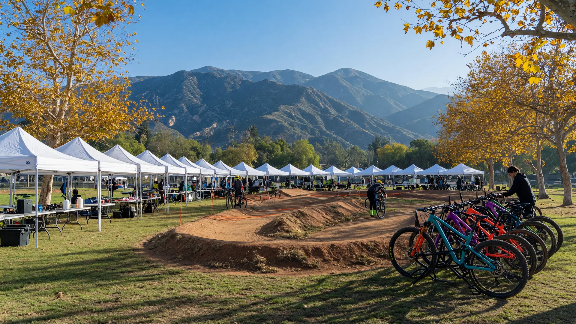 An outdoor cycling festival with canopy tents, a bermed bike demo course, and colorful bikes in a Southern California park