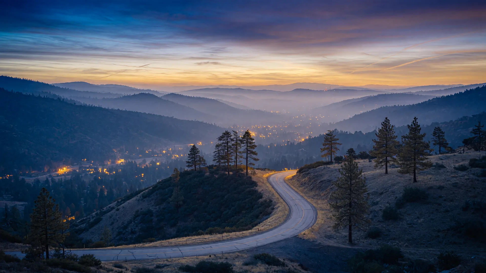 Layered Sierra foothill ridgelines and a valley at blue-gold dusk