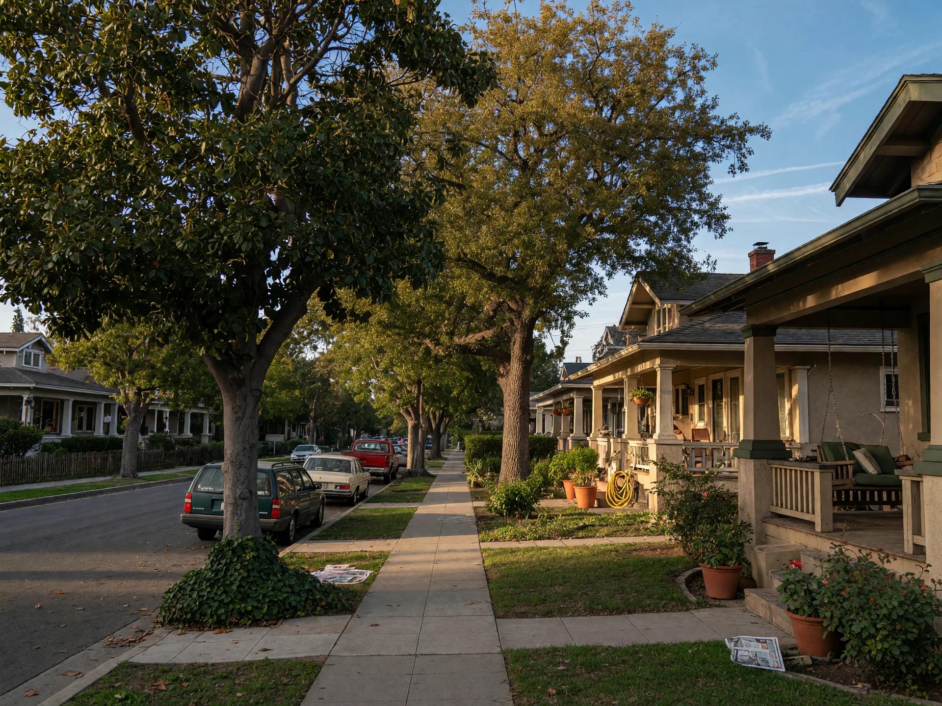 A tree-lined Pasadena street of Craftsman bungalows in the late afternoon, the everyday backdrop of the city's cost of living