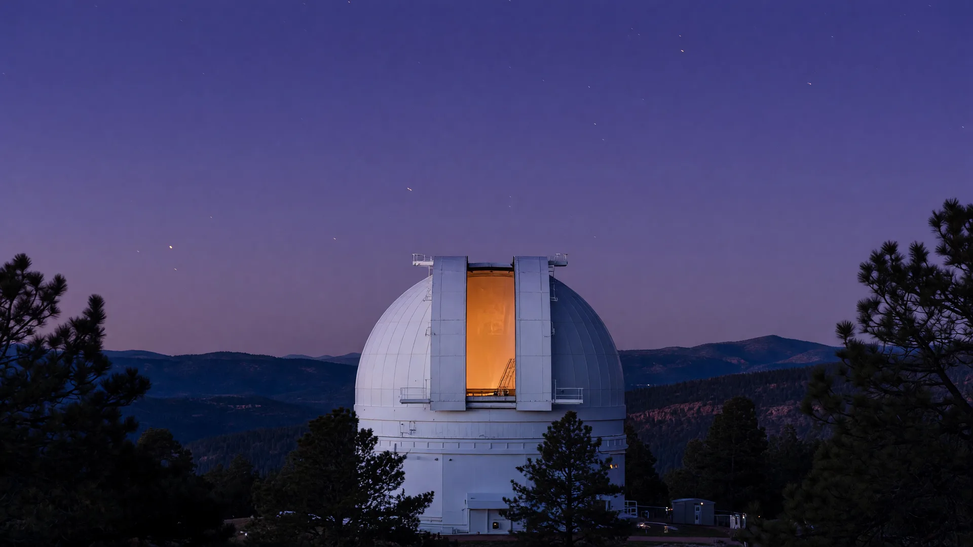 The classic white observatory dome at Lowell Observatory in Flagstaff at dusk under a deep twilight sky