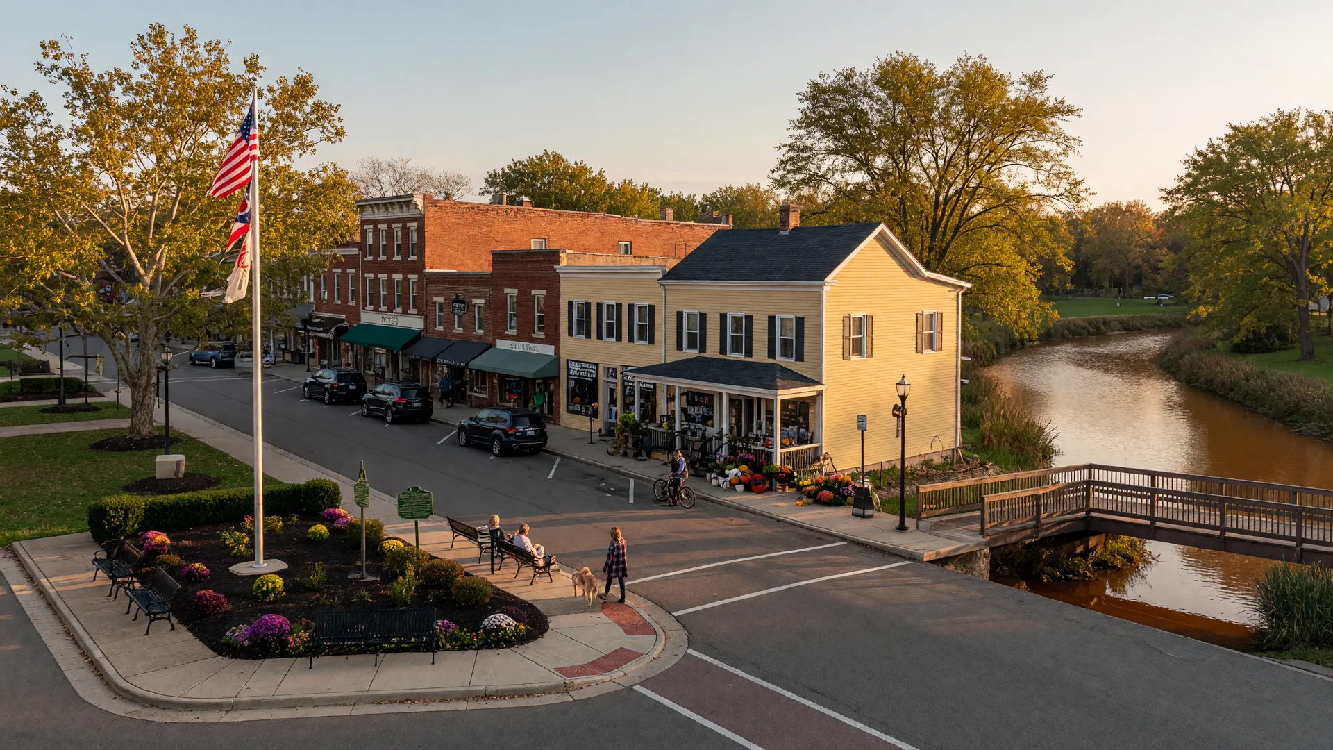 Charming downtown Powell Ohio with brick and clapboard shops, Olentangy River footbridge, and mature trees at golden hour