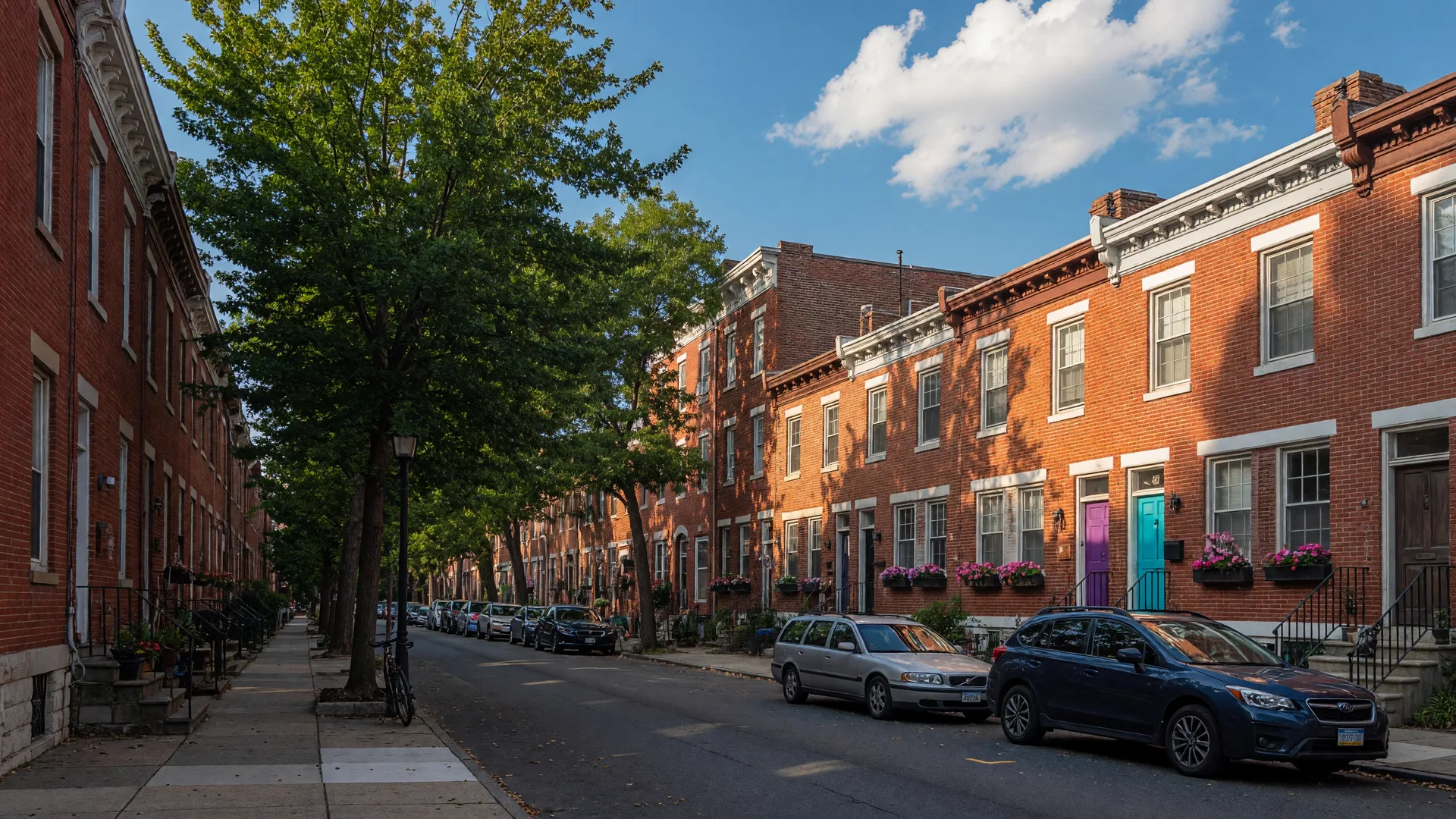 Sunny residential street in Washington Square West with historic brick rowhomes and mature trees