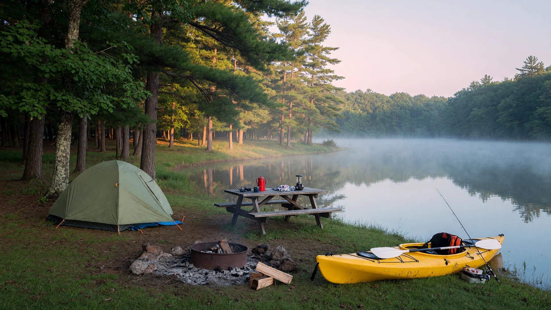Peaceful lakeside campground on Chickahominy Lake in Virginia with a tent, campfire ring, and fishing kayak in the morning mist