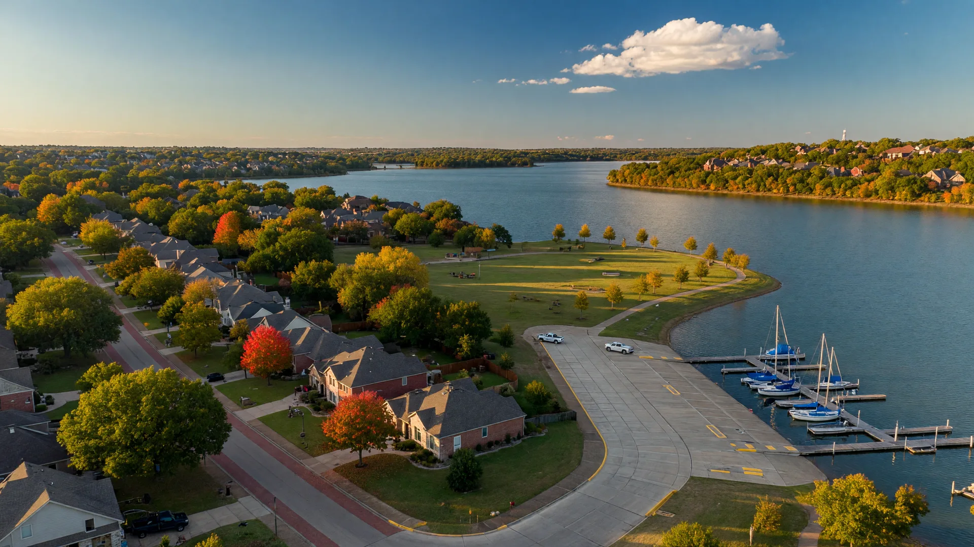 Aerial view of a suburban lake community near Hickory Creek TX with homes, tree canopy, and a wide reservoir in fall