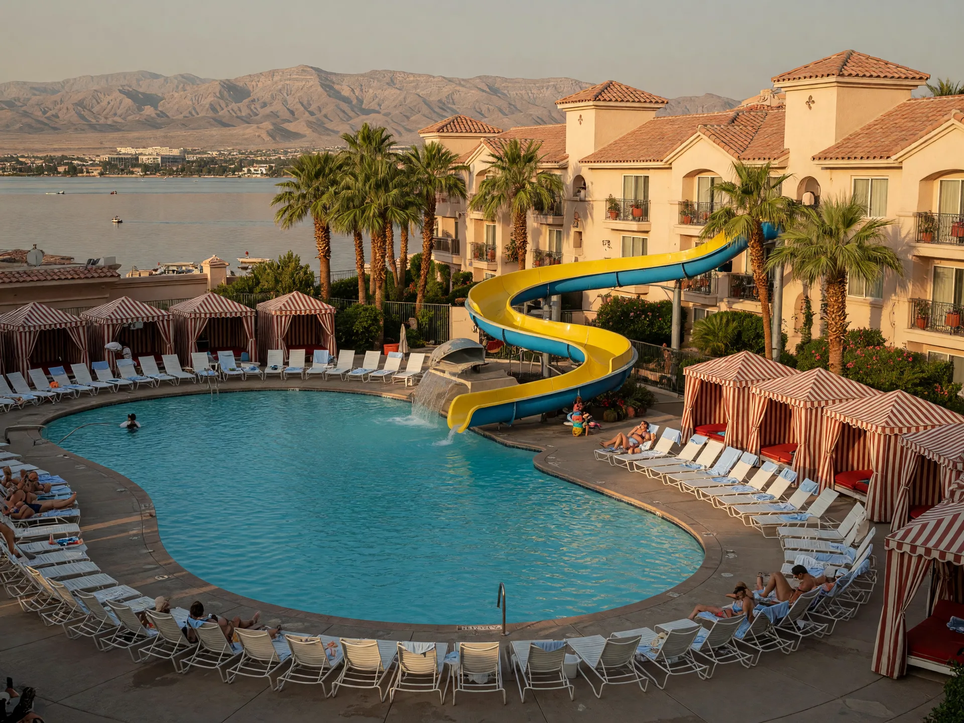 A lakeside resort pool at Lake Las Vegas with turquoise water, loungers, cabanas and palm trees in front of the hotel
