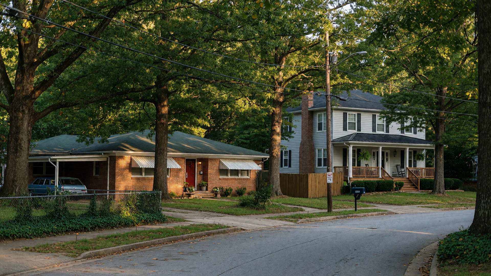 Tree-lined residential street in Cascade Heights, southwest Atlanta, with an older brick ranch and a newer two-story home among mature hardwoods