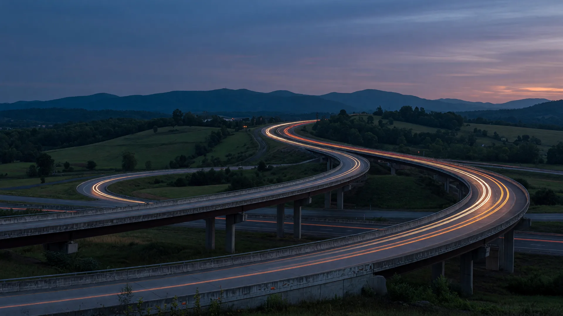 Highway interchange at dusk in western Maryland with light trails and distant mountains