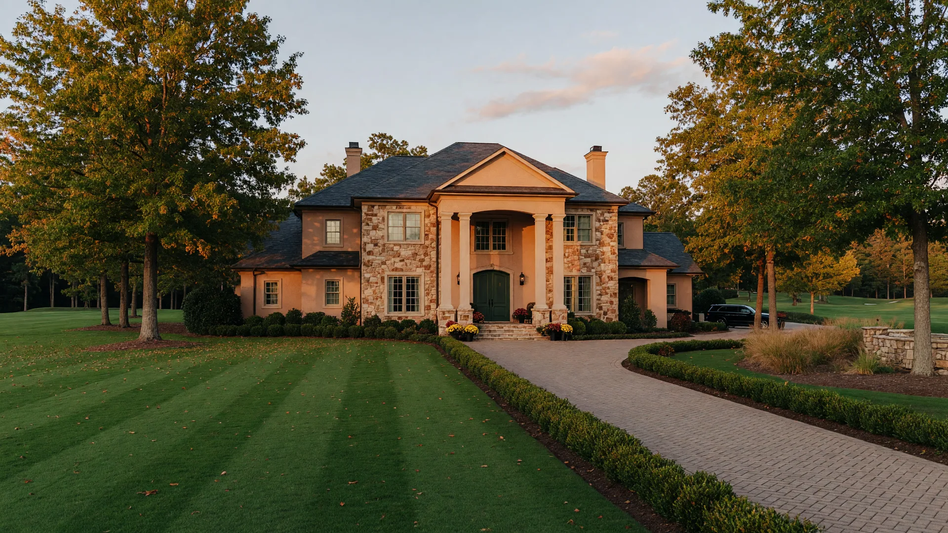 Luxury stone and stucco estate home in an upscale Georgia golf course community at golden hour in early autumn with amber leaves