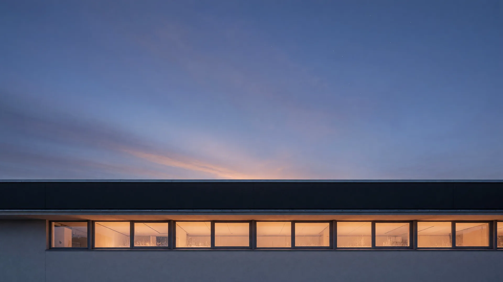 Warm light glowing from long windows at dusk