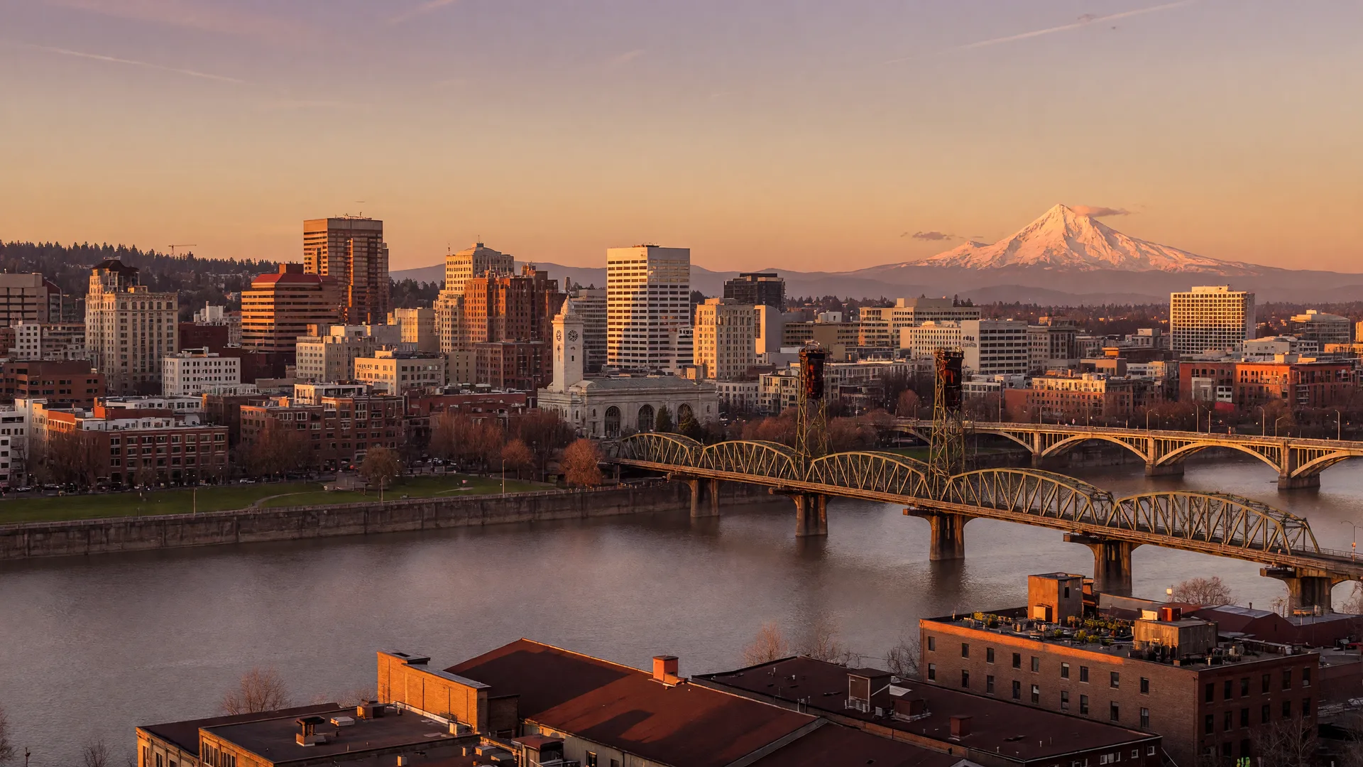 Portland skyline at golden hour with Mount Hood on the eastern horizon and the Willamette River in the foreground