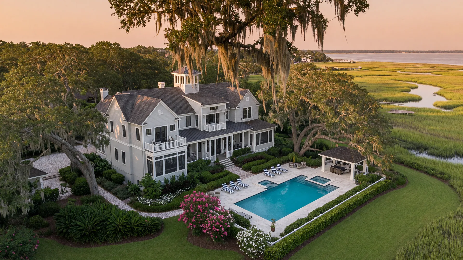 Aerial view of a luxury Lowcountry estate, golf course, and live oaks at golden hour