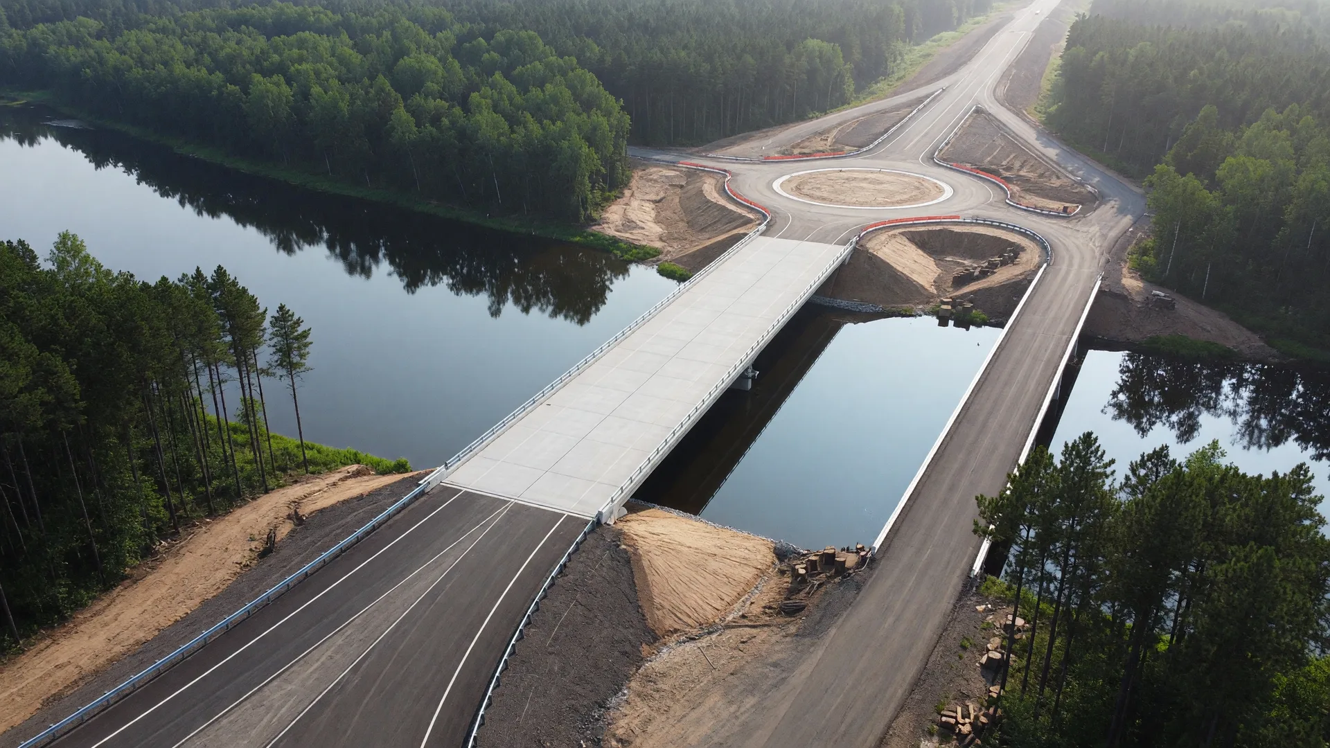 Aerial view of a new two-lane highway bridge crossing a calm river